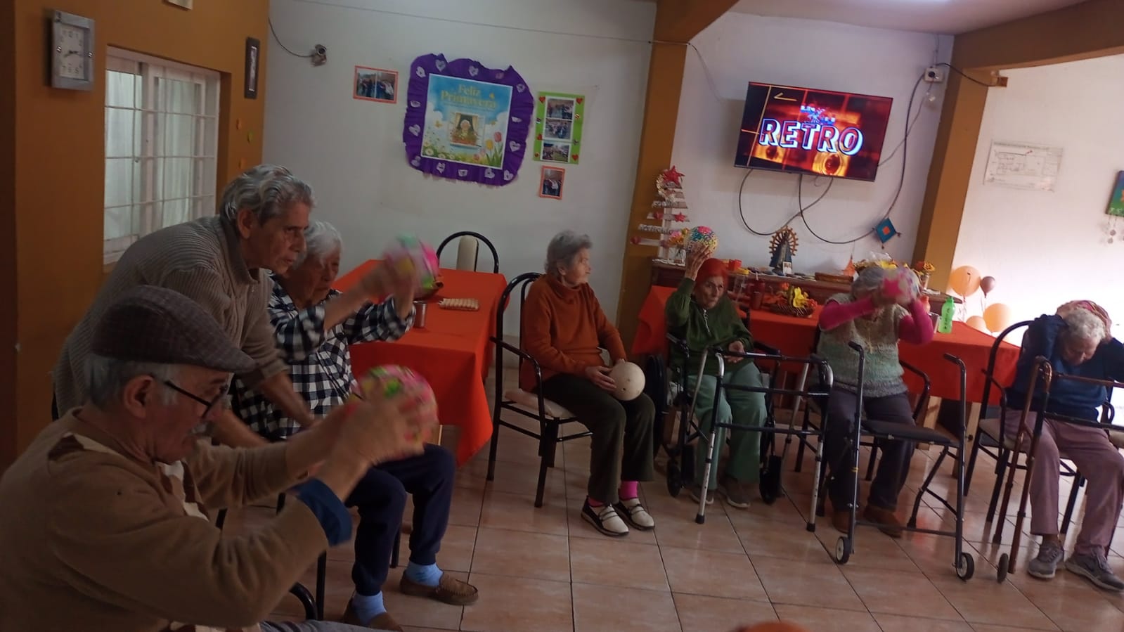 Personas participan de una actividad grupal con pelotas en el salón.