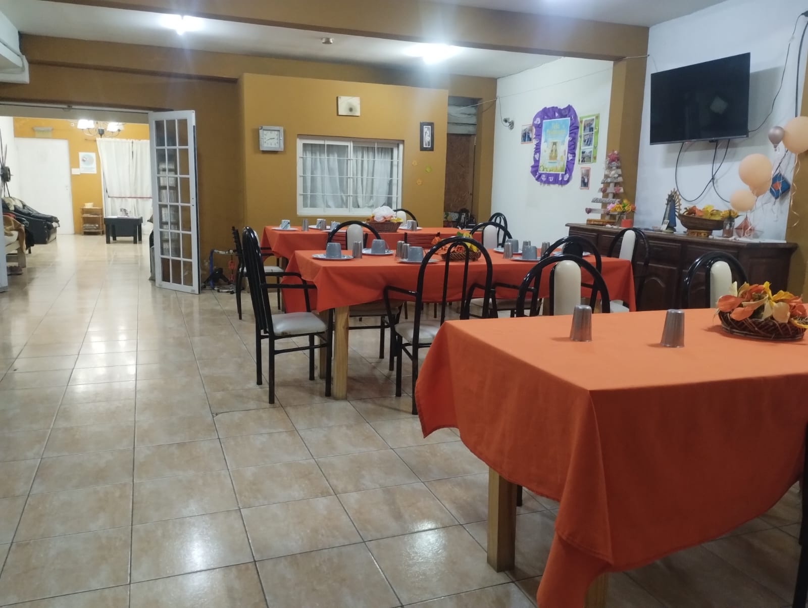 Comedor del hogar con mesas preparadas y espacios comunes al fondo.