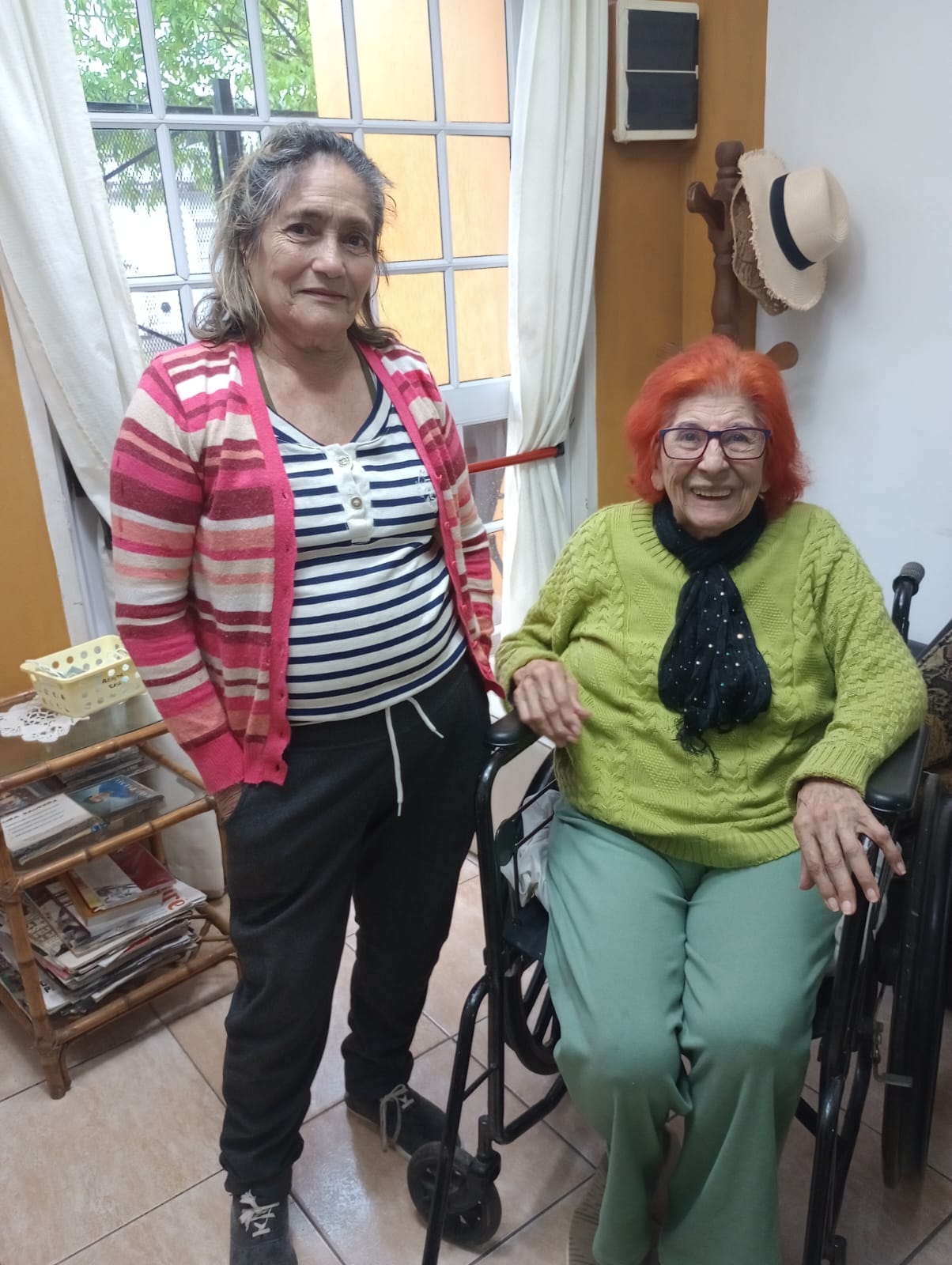 Dos personas comparten un momento junto a una ventana del hogar.