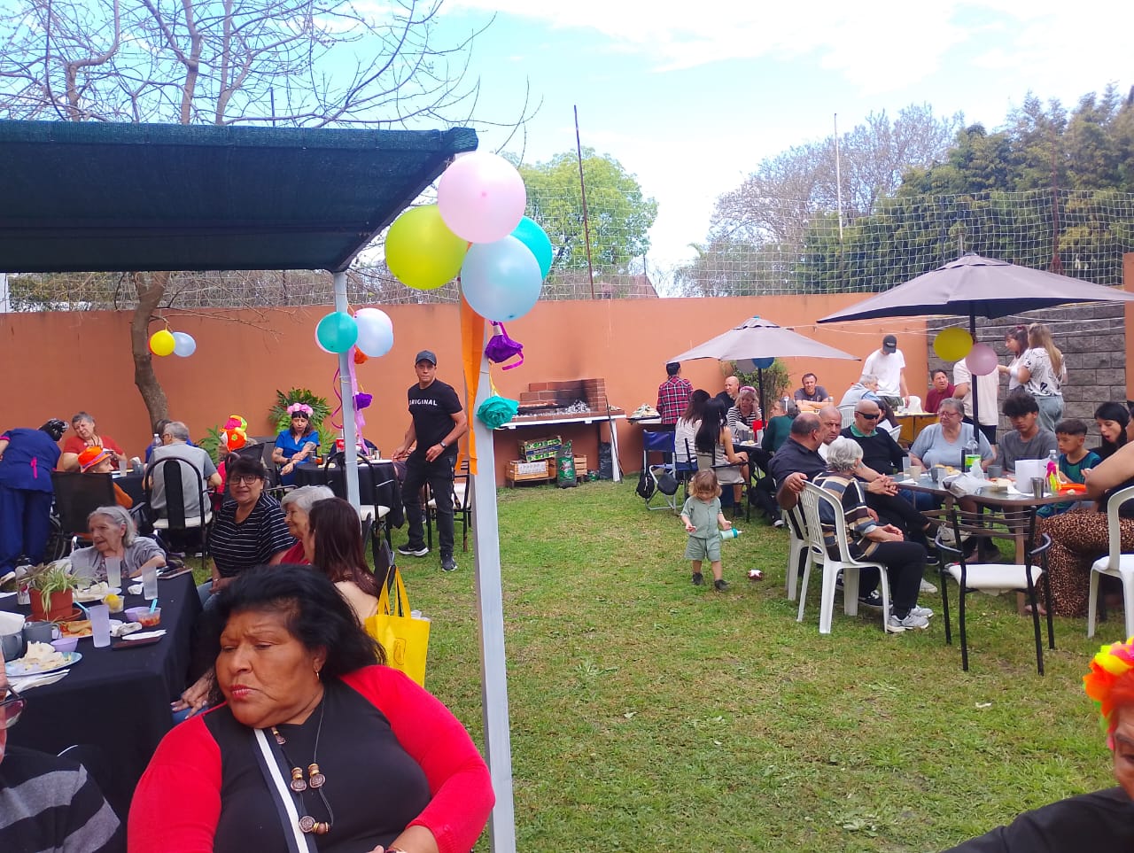 Mesas y personas reunidas durante una celebración en el jardín.